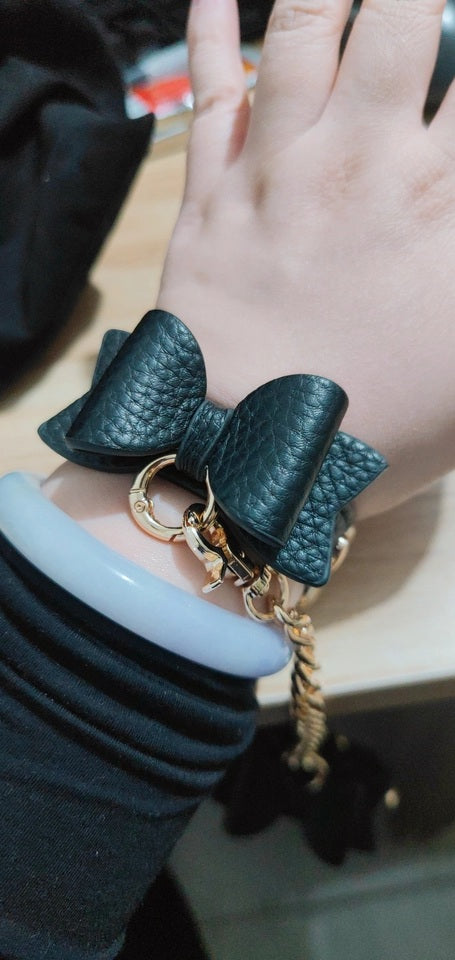 Modelled photo of black and gold bow wristband showing the kawaii ribbon bow design and gold tone hardware