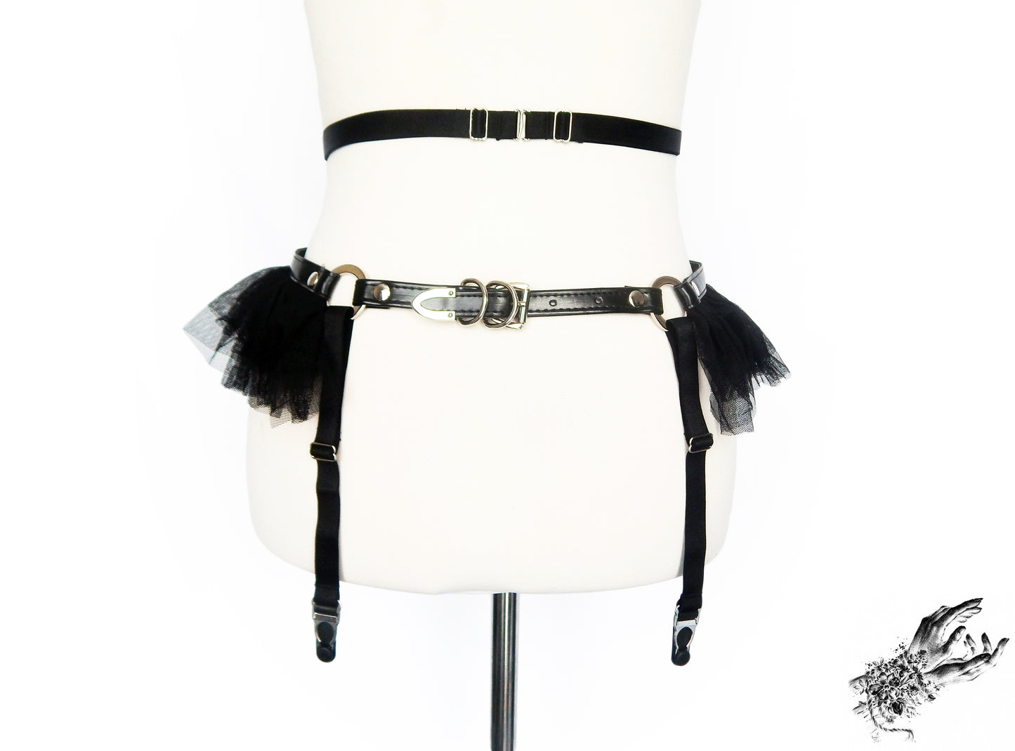 Rear view of a black vegan leather garter belt showing the adjustable elastic waist straps, suspender straps and faux leather buckled hip strap, displayed on a mannequin against a white background.