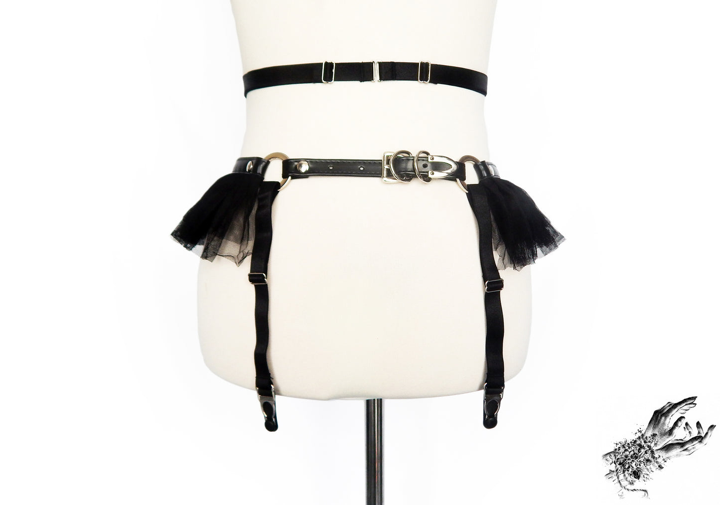 Rear view of a black faux leather garter belt showing a sliding elastic waist strap and adjustable buckled faux leather hip strap, displayed on a mannequin against a white background.