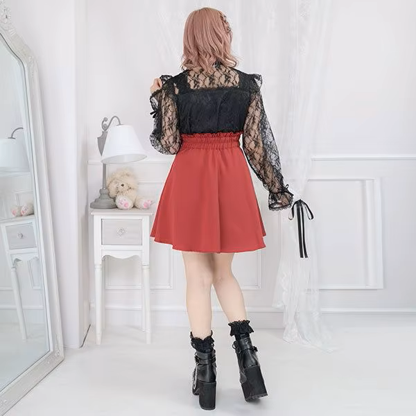 Modelled photo of the back of a red high waisted skirt featuring a partially elasticated waist, side zip fastening and pleated a-line design, styled with a black blouse and chunky black Mary Jane shoes for a Jirai Kei fashion aesthetic.