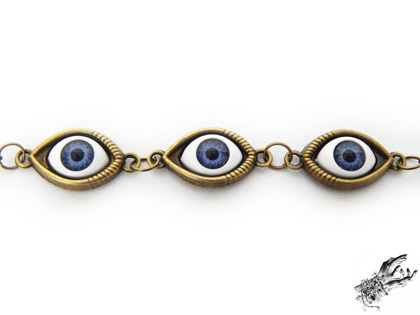 Close-up of the antique bronze evil eye bracelet, showing navy blue irises in bronze cameo frames, creating a vintage fashion aesthetic