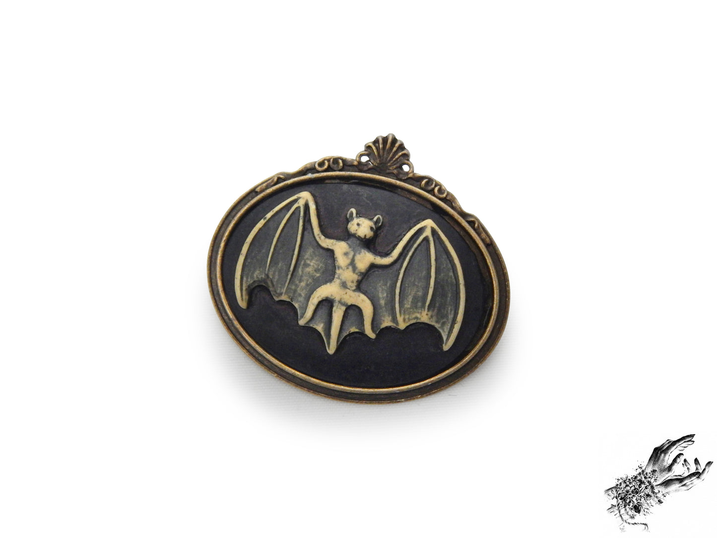 Antique bronze brooch featuring a black and ivory resin bat cameo in an ornate bronze frame, inspired by Victorian gothic fashion and mourning jewellery in the UK