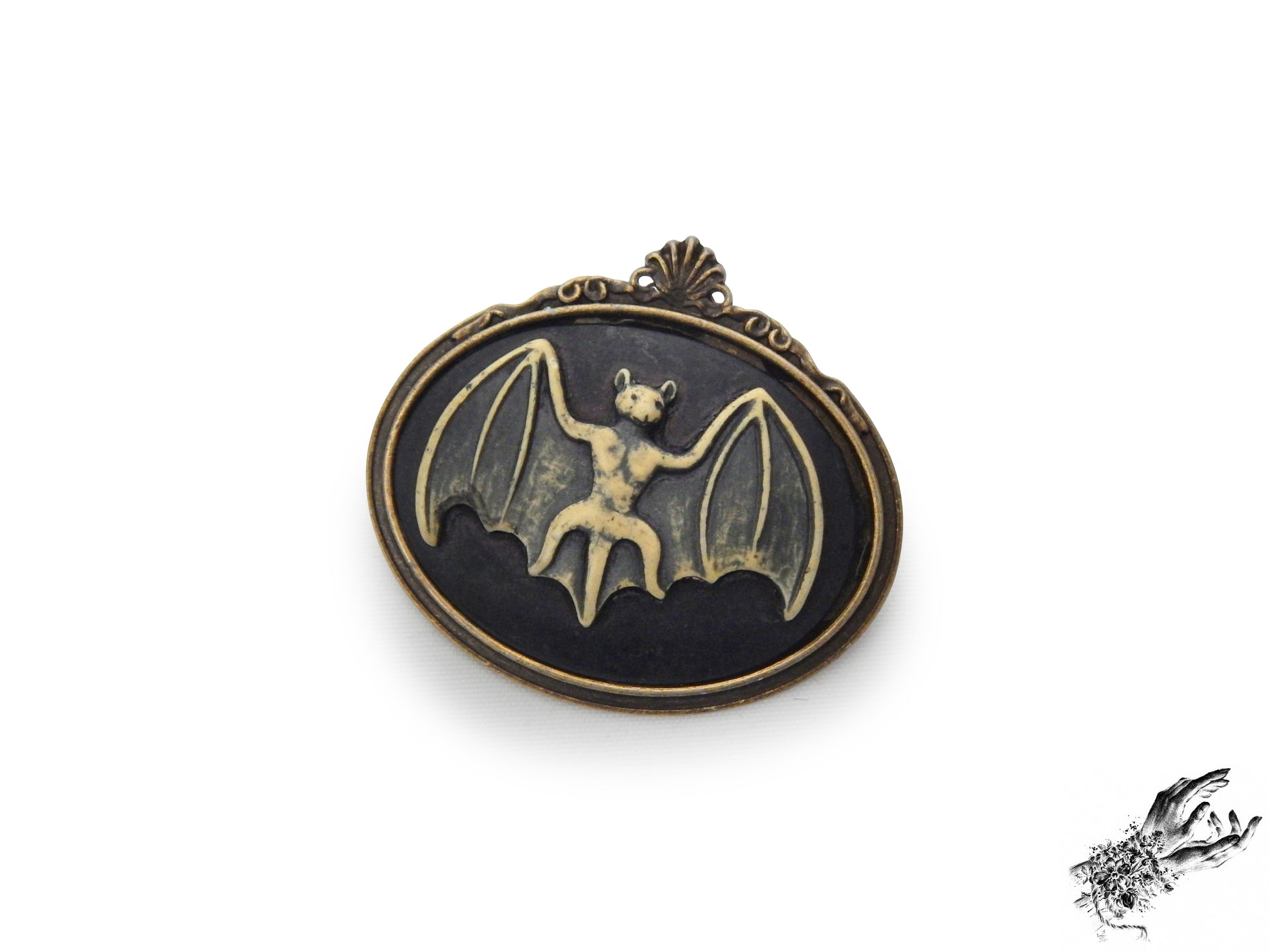 Antique bronze brooch featuring a black and ivory resin bat cameo in an ornate bronze frame, inspired by Victorian gothic fashion and mourning jewellery in the UK