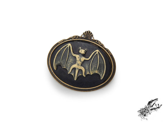 Antique bronze brooch featuring a black and ivory resin bat cameo in an ornate bronze frame, inspired by Victorian gothic fashion and mourning jewellery in the UK