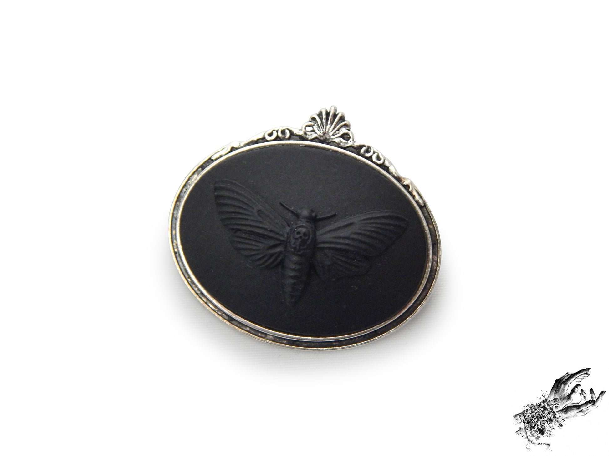 Antique silver brooch featuring a black resin deathshead moth cameo in an ornate silver plated frame, inspired by Victorian gothic fashion and mourning jewellery in the UK