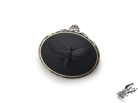Antique silver brooch featuring a black resin deathshead moth cameo in an ornate silver plated frame, inspired by Victorian gothic fashion and mourning jewellery in the UK