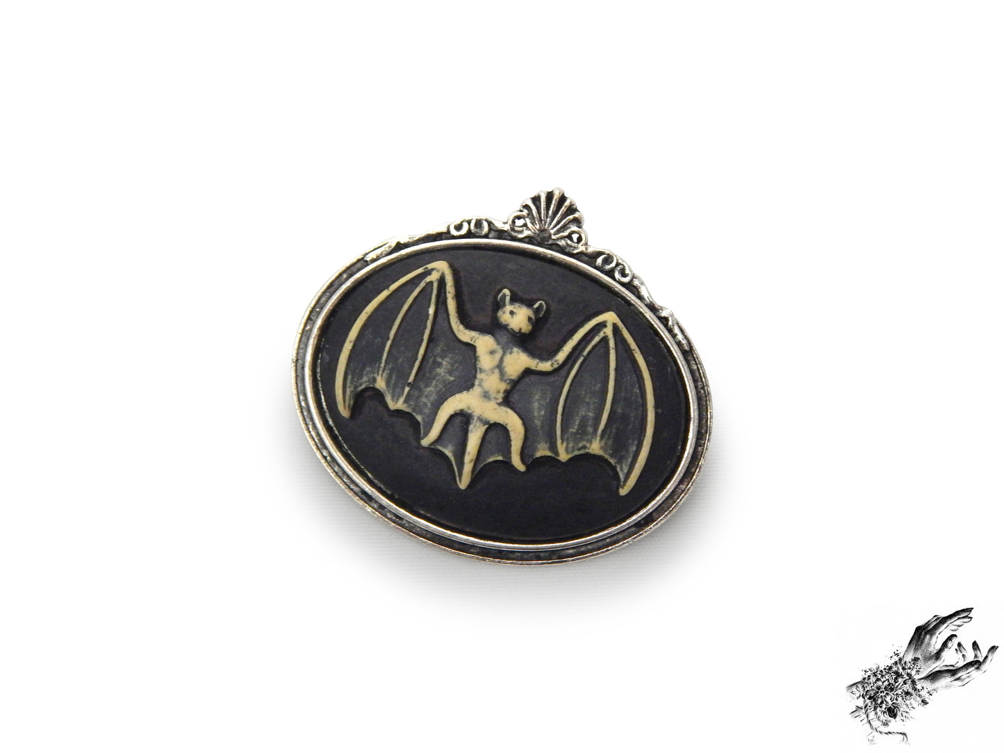 Antique silver brooch featuring a black and ivory resin bat cameo in an ornate silver plated frame, inspired by Victorian gothic fashion and mourning jewellery in the UK
