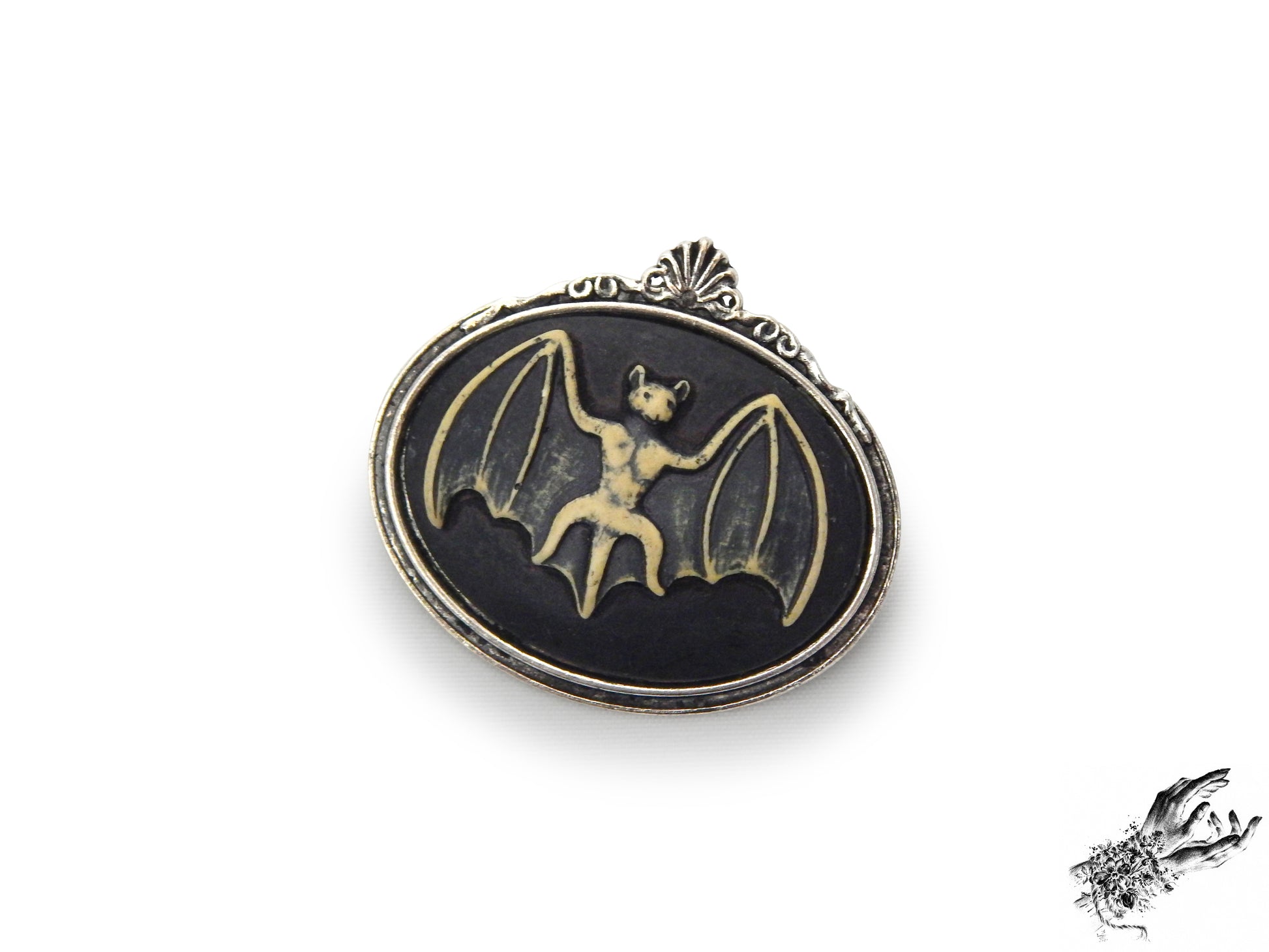 Antique silver brooch featuring a black and ivory resin bat cameo in an ornate silver plated frame, inspired by Victorian gothic fashion and mourning jewellery in the UK