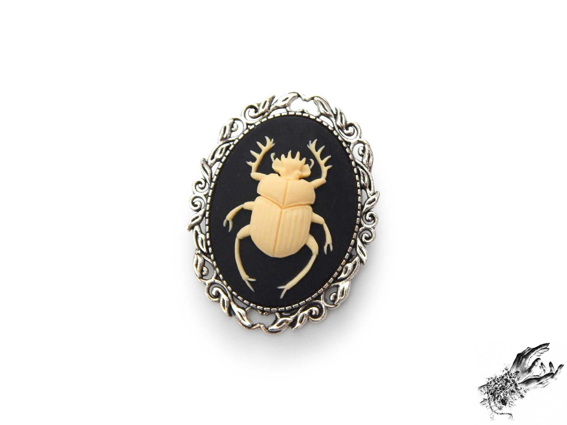 Antique silver brooch featuring a black and ivory resin beetle cameo in an ornate silver plated frame, inspired by Victorian gothic fashion and mourning jewellery in the UK