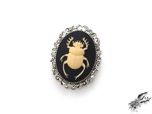 Antique silver brooch featuring a black and ivory resin beetle cameo in an ornate silver plated frame, inspired by Victorian gothic fashion and mourning jewellery in the UK