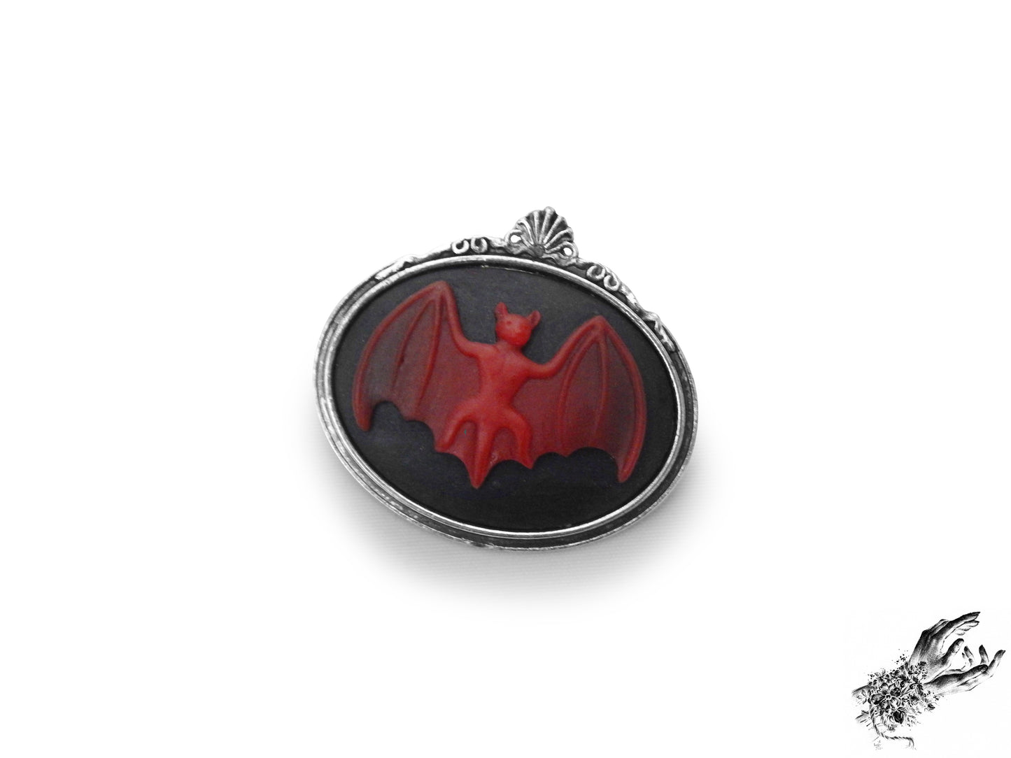 Antique silver brooch featuring a black and red resin bat cameo in an ornate silver plated frame, inspired by Victorian gothic fashion and mourning jewellery in the UK