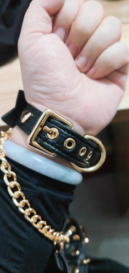 Customer photo of black and gold bow wristband, made with real leather and gold tone hardware, showing the adjustable buckle and holes