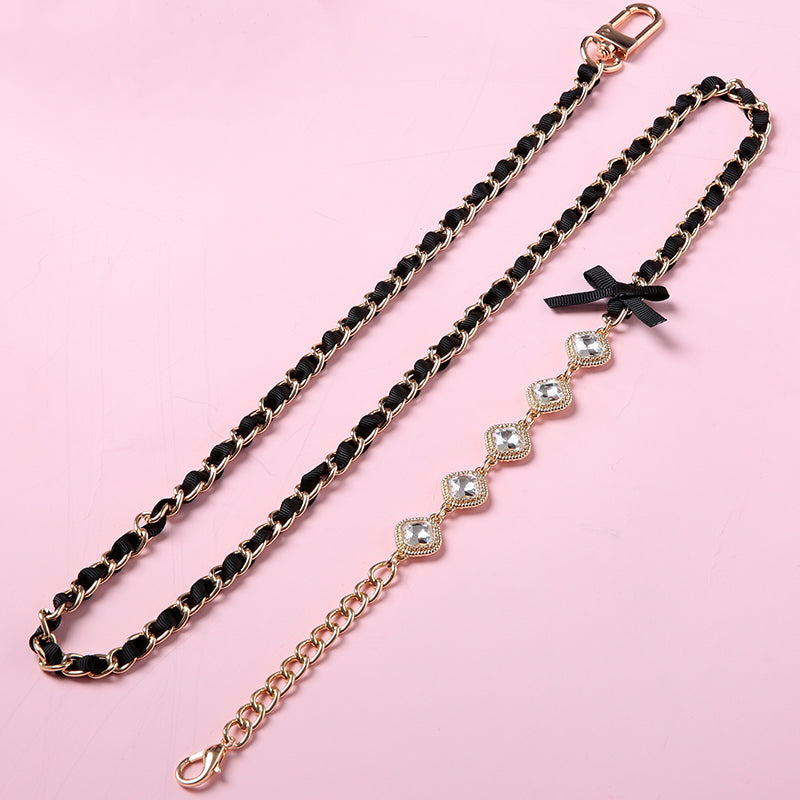 Gold tone chain leash showing the black satin ribbon threaded through the chain links, black satin bow details, diamante connector charms and swivelling lobster clasp