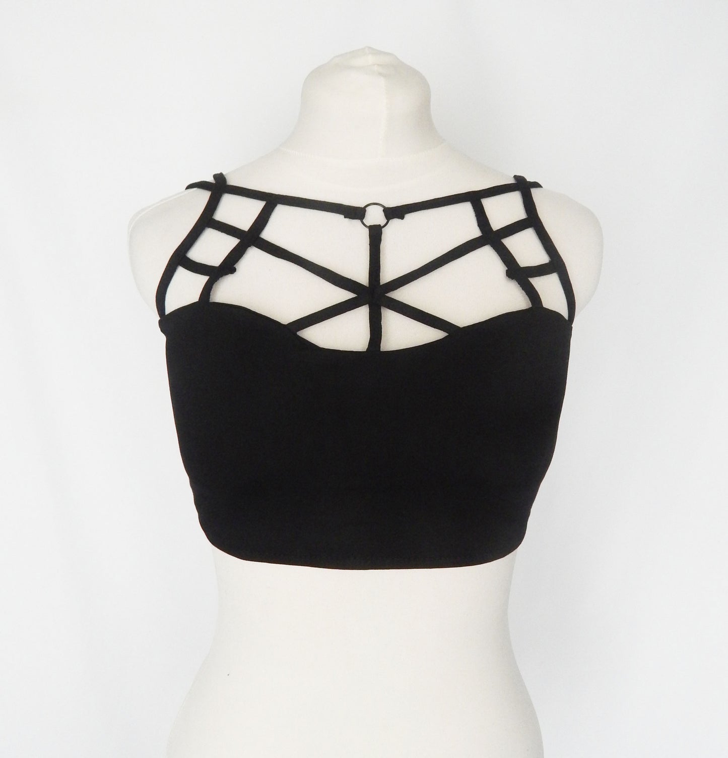 Black strappy tube top featuring geometric criss-cross straps on the chest, displayed on a white mannequin torso against a white background.