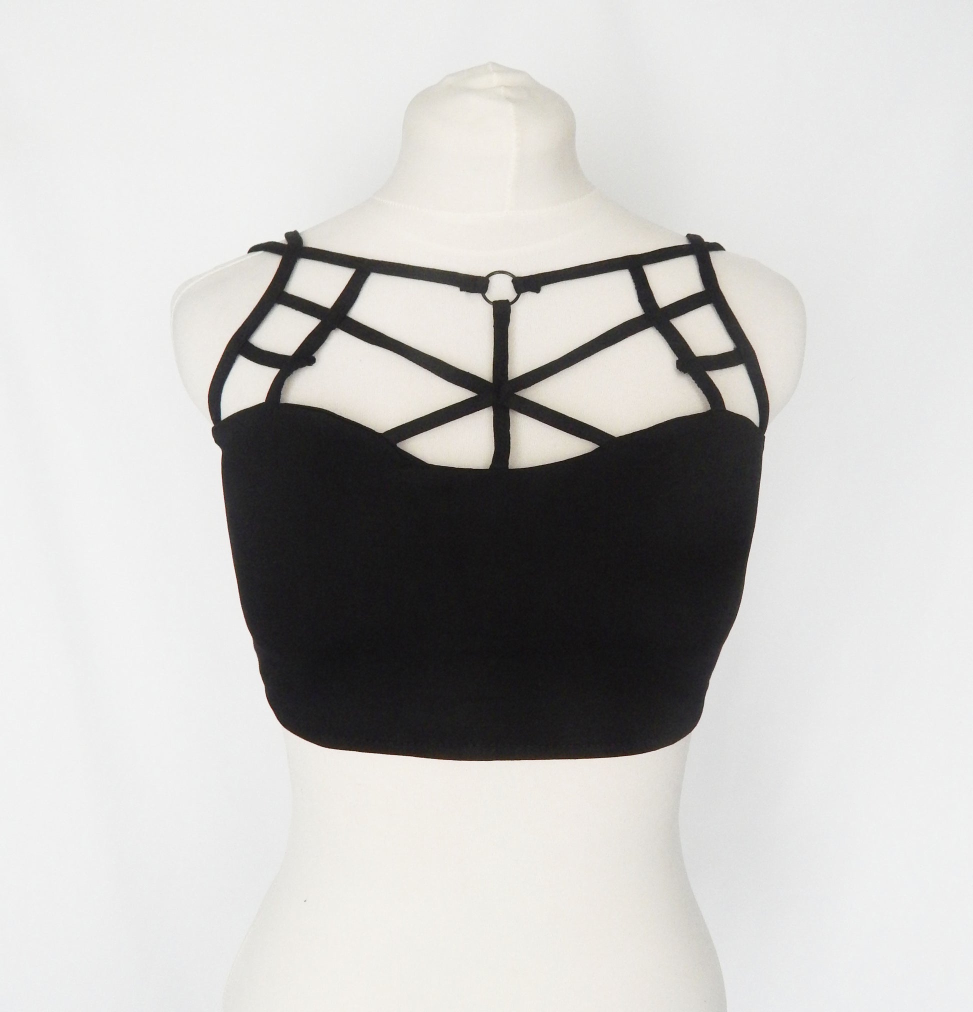 Black strappy tube top featuring geometric criss-cross straps on the chest, displayed on a white mannequin torso against a white background.