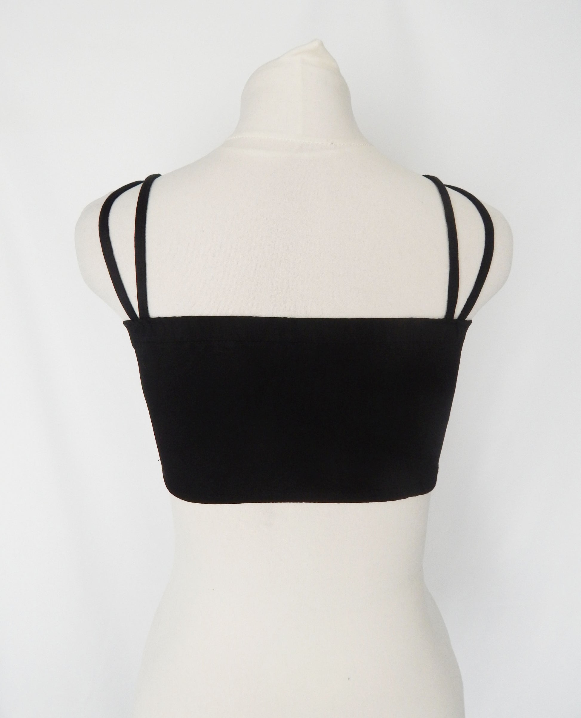 Rear view of a black strappy crop top showing the stretchy shoulder straps, displayed on a white mannequin against a white background.