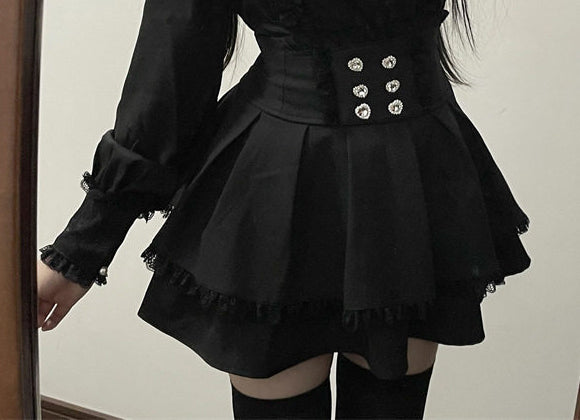 A person wearing a black long-sleeve mini skirt with a structured waist, decorative silver-tone buttons, and ruffled trim, paired with black thigh-high stockings.