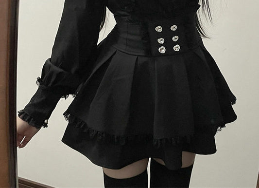 A person wearing a black long-sleeve mini skirt with a structured waist, decorative silver-tone buttons, and ruffled trim, paired with black thigh-high stockings.