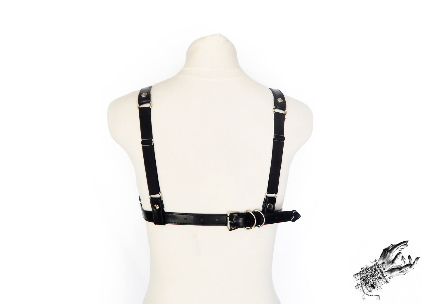 Rear view of a black faux leather harness bra showing the fully adjustable shoulders and back with satin elastic straps and buckle fastening. Displayed on a white mannequin against a white background.