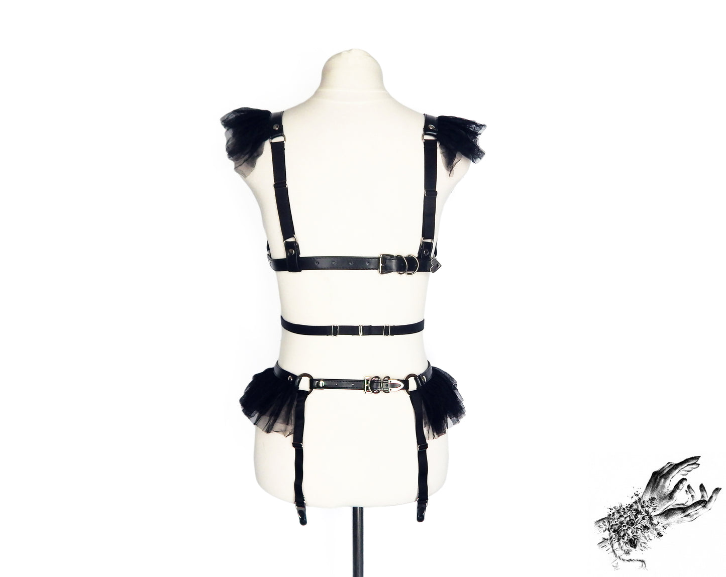 Rear view of a black vegan leather harness set showing the adjustable faux leather buckled straps and sliding elastic straps, displayed on a mannequin against a white background.