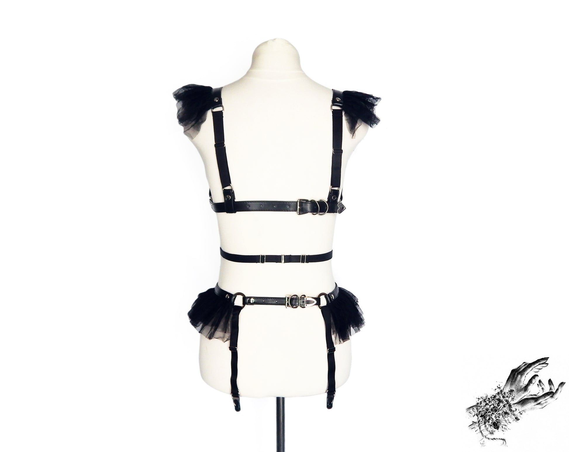 Rear view of a black vegan leather harness set showing the adjustable faux leather buckled straps and sliding elastic straps, displayed on a mannequin against a white background.