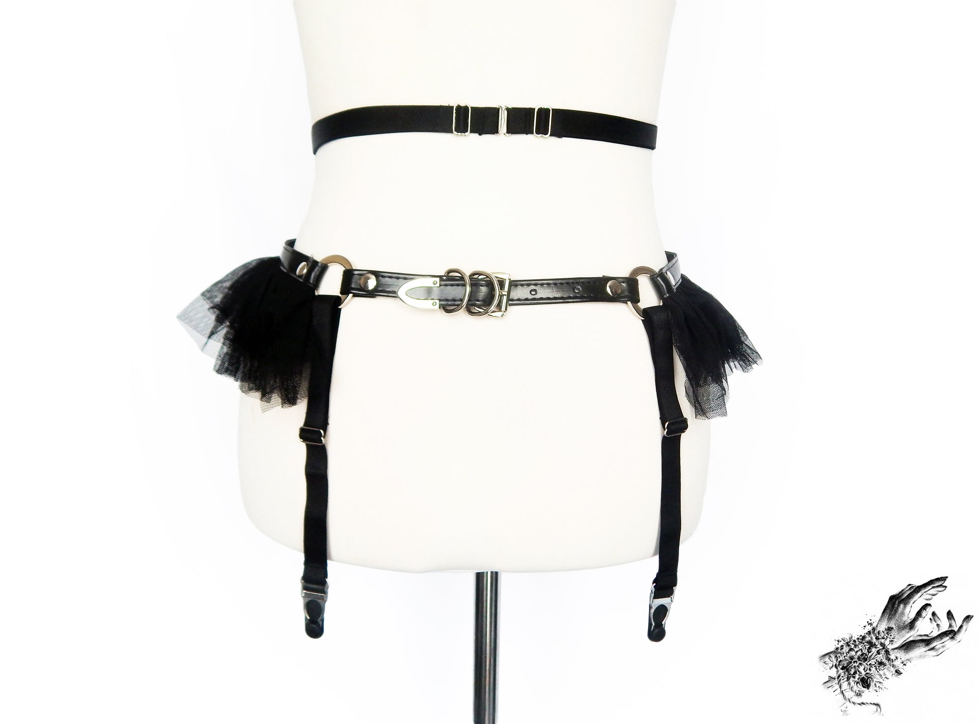 Rear view of a black vegan leather garter belt showing the adjustable elastic waist straps, suspender straps and faux leather buckled hip strap, displayed on a mannequin against a white background.