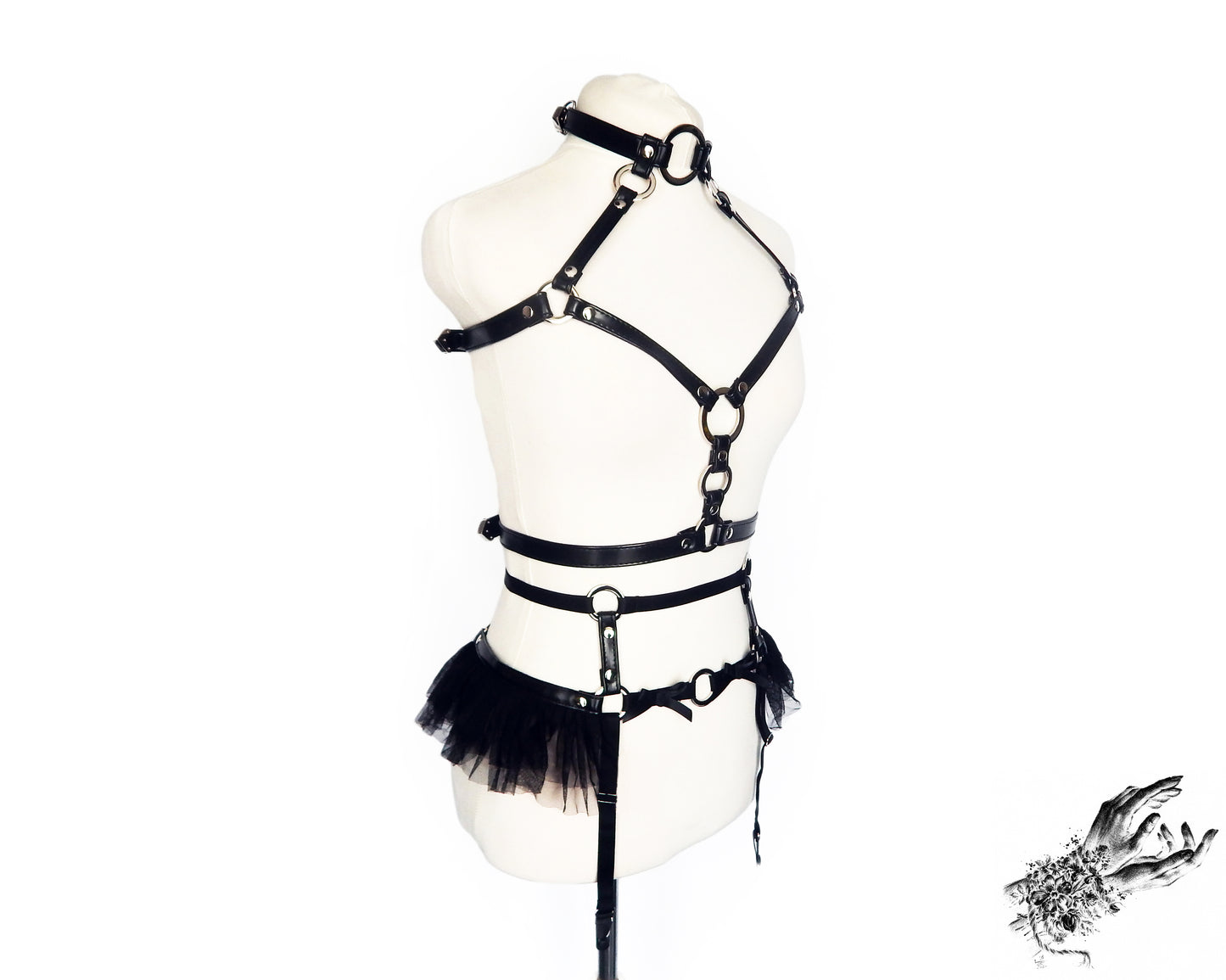 Black vegan leather harness set featuring silver O ring hardware, ruffled tulle and bow appliques, displayed on a mannequin against a white background.