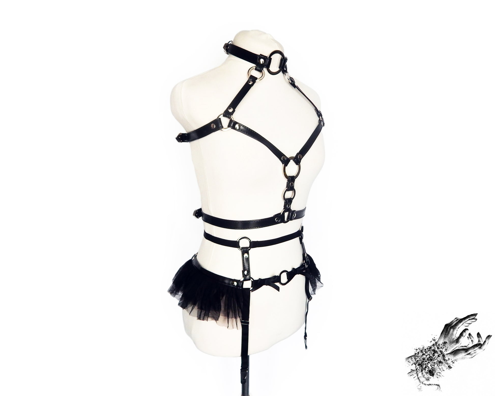 Black vegan leather harness set featuring silver O ring hardware, ruffled tulle and bow appliques, displayed on a mannequin against a white background.