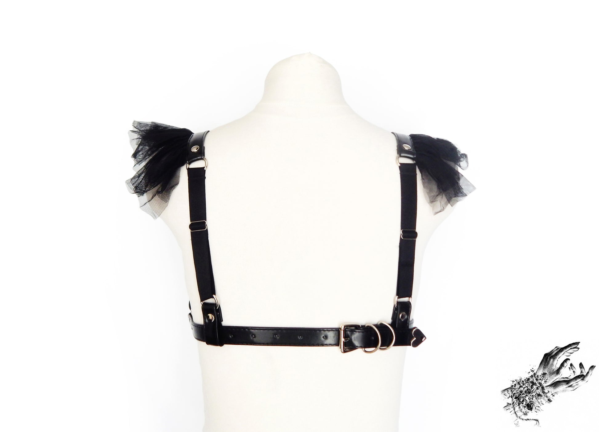 Rear view of a black vegan leather harness bra showing the sliding elastic shoulder straps and buckled underbust strap, displayed on a mannequin against a white background.