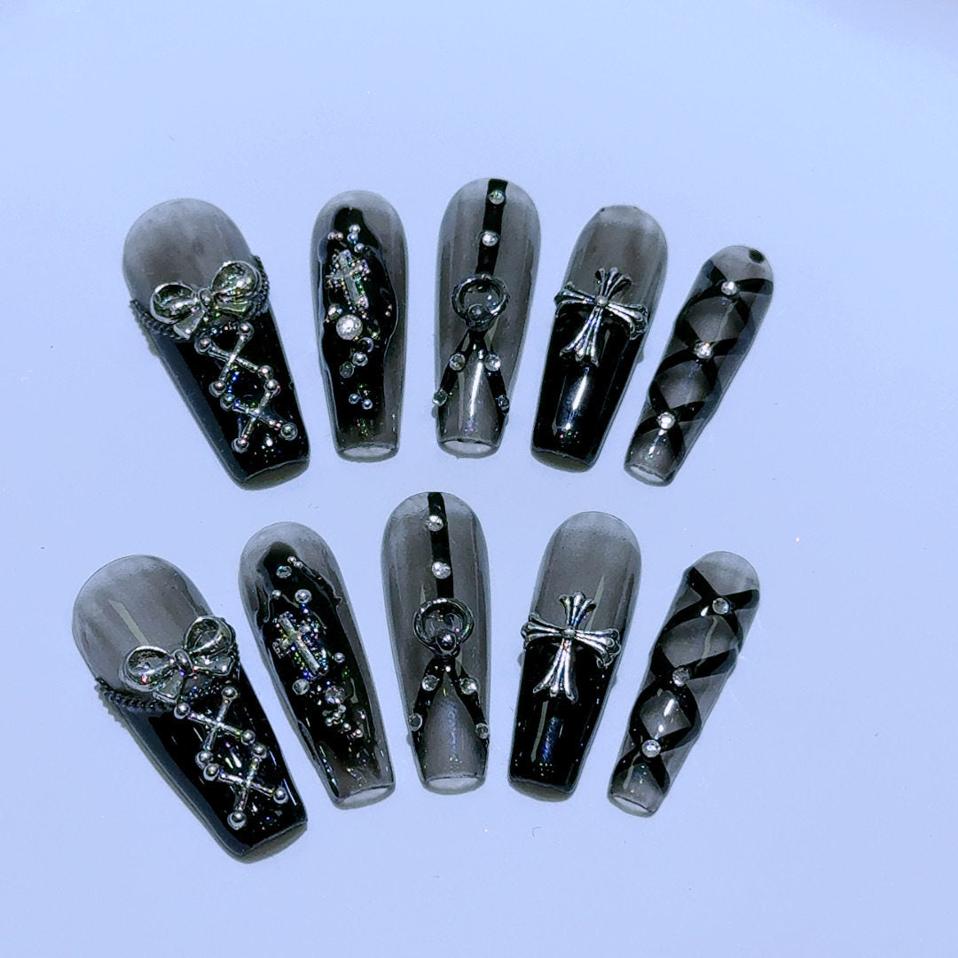 black and silver false nails displayed on a grey background, featuring 3D silver bows, crosses, O rings, clear diamantes and black bondages straps for a BDSM fashion aesthetic.