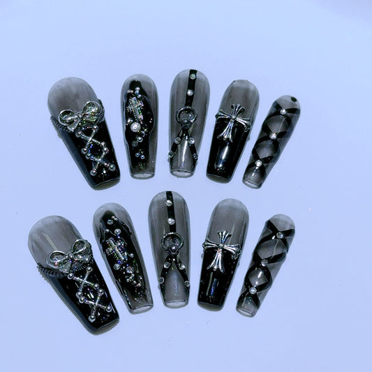 black and silver false nails displayed on a grey background, featuring 3D silver bows, crosses, O rings, clear diamantes and black bondages straps for a BDSM fashion aesthetic.