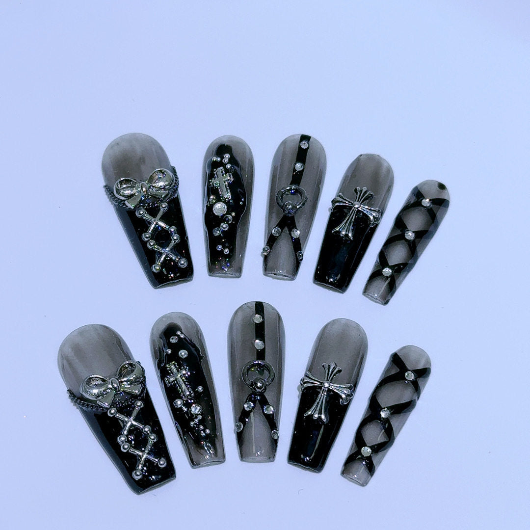 black and silver false nails displayed on a grey background, featuring 3D silver bows, crosses, O rings, clear diamantes and black bondages straps for a gothic Gyaru aesthetic.