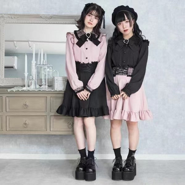 Two models wearing pink and black long sleeved blouses with Peter Pan style collars, ruffled shoulders, pintucks, heart shaped buttons and detachable bow brooches. Styled with black and pink ruffled shirts and Mary Jane shoes for a Jirai Kei aesthetic.