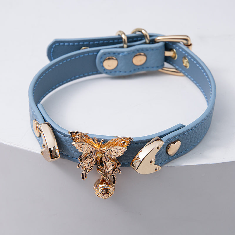 Blue leather choker featuring ornate gold butterfly and bell hardware and an adjustable gold tone buckle at the back, designed for pastel goth and fairy kei fashion in the UK