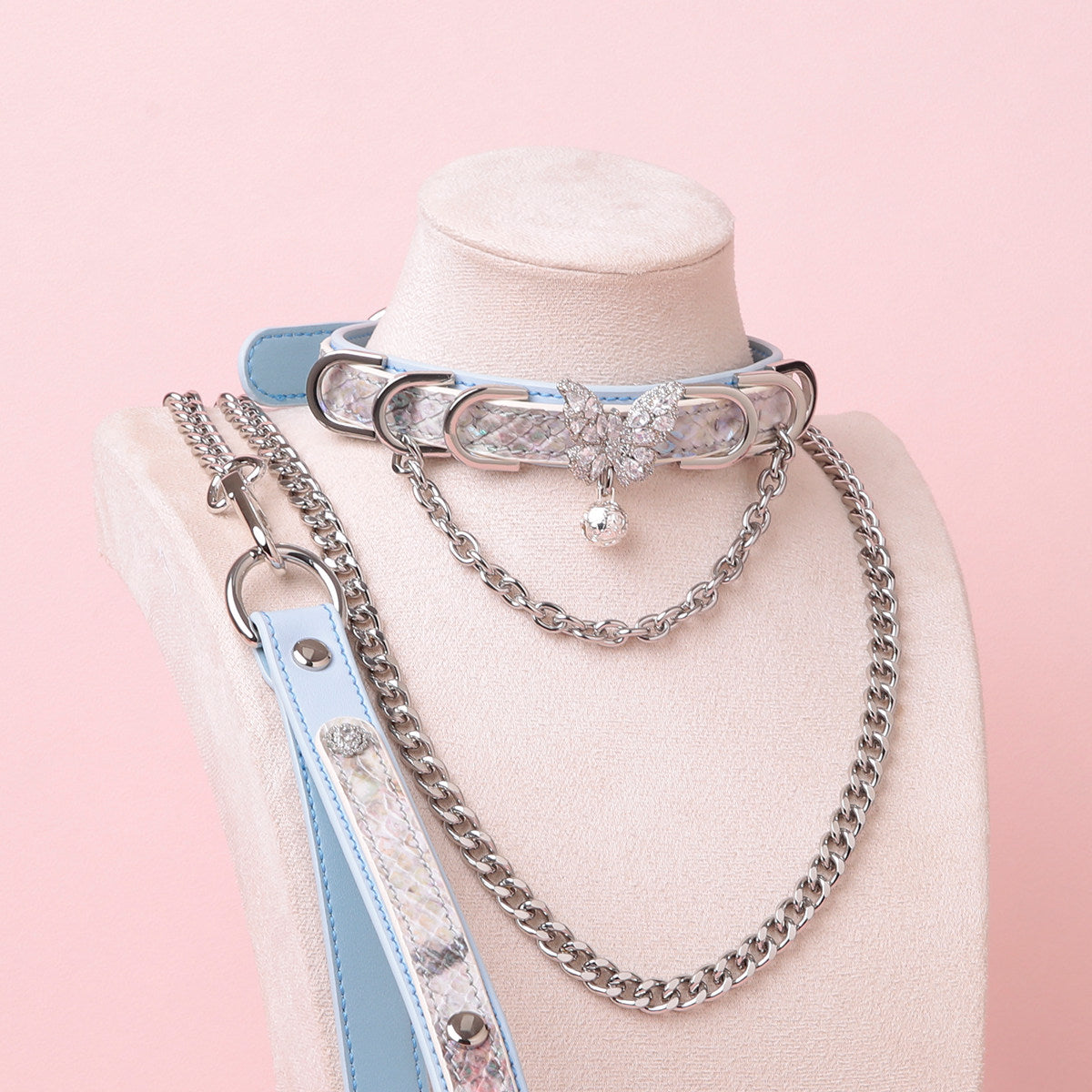 Blue leather choker and leash set featuring a silver diamante butterfly charm, chains, D rings and bell, with detachable chain leash and leather hand strap. Displayed on a white mannequin bust against a pink background for a Harajuku fashion aesthetic.