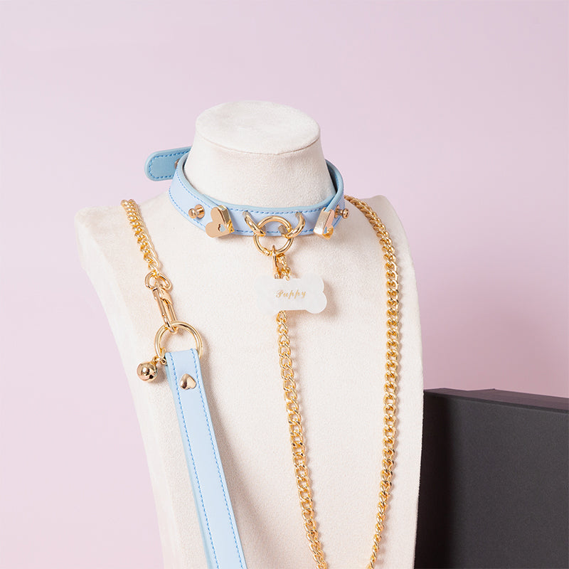 Baby blue leather choker featuring gold tone hardware, custom engraved bone shaped pet tag, heavy duty chain leash and leather hand strap. Displayed on a white mannequin bust against a light pink background for a kawaii aesthetic.