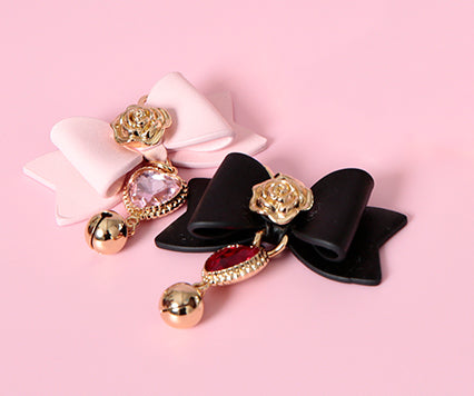 Detachable bow charms in black and pink leather, showing the ornate gold flower hardware in the centre of the bow, diamante heart charms and dainty gold bells