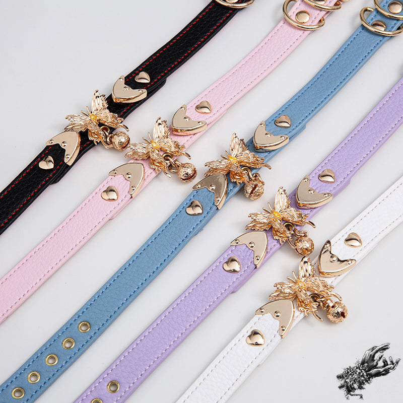 Leather chokers featuring ornate gold butterfly and bell hardware, with leather colours in black, pink, blue, lilac and white