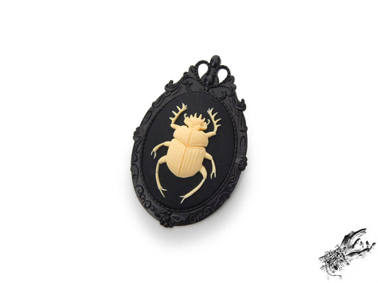 Gunmetal black brooch featuring a black and ivory resin beetle cameo in an ornate black enamel plated frame, inspired by Victorian gothic fashion and mourning jewellery in the UK