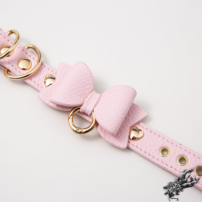Pink leather wristband with kawaii bow design and gold hardware, designed in the UK for kawaii and pastel goth fashion