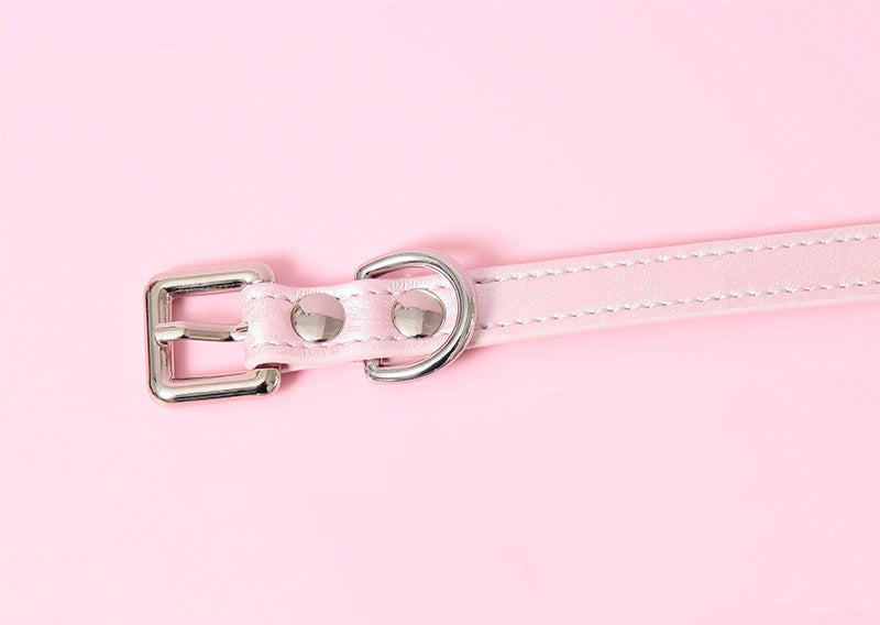 Close-up of a pink leather choker showing the stainless steel plated buckle and D ring hardware, ensuring a durable and versatile fit. Displayed on a pink background for a kawaii fashion aesthetic.