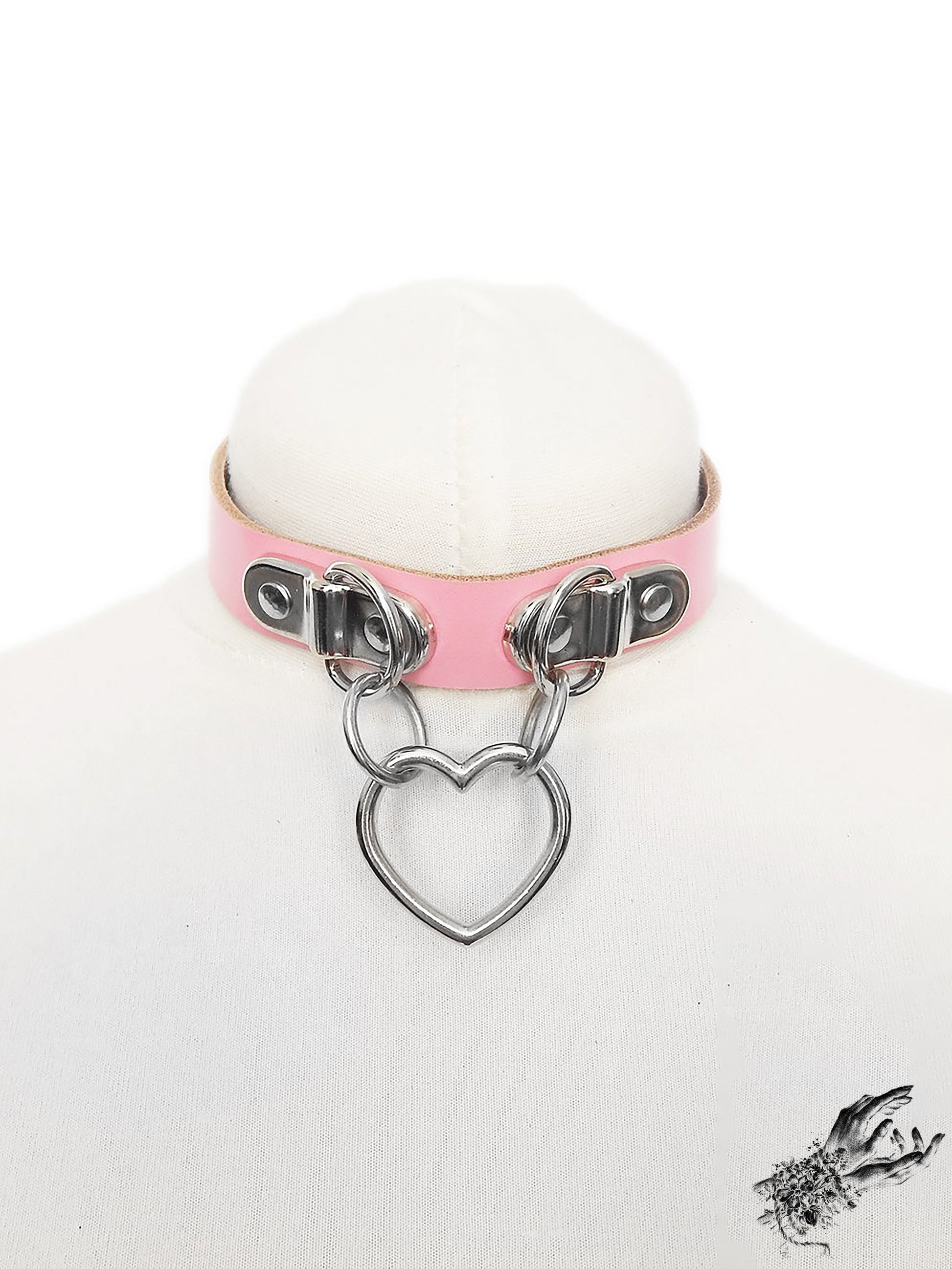 Pink leather collar with a silver heart-shaped pendant on a white mannequin bust