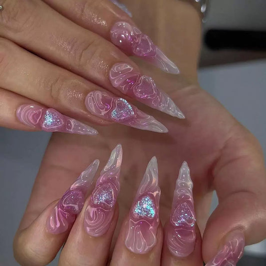 Long, sculpted stiletto false nails decorated with pink and clear 3D swirls and glittery pink hearts.