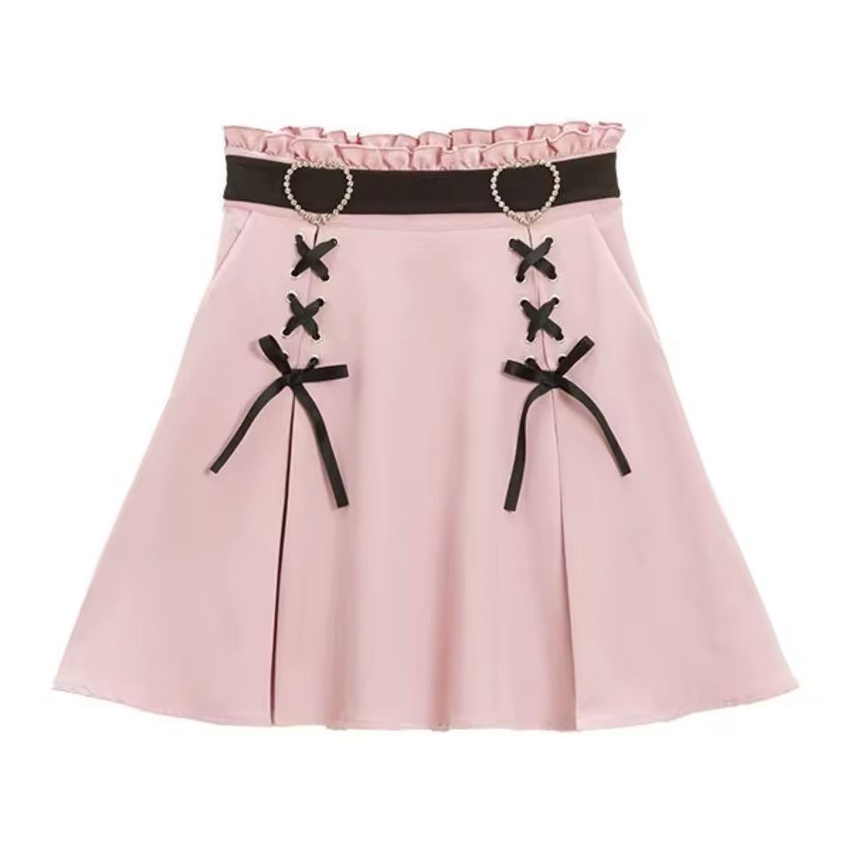 Pink and black high waisted skirt featuring a ruffled waist, diamante heart shaped buckle belt, satin ribbon corset lacing and pleated a-line design, displayed against a white background.
