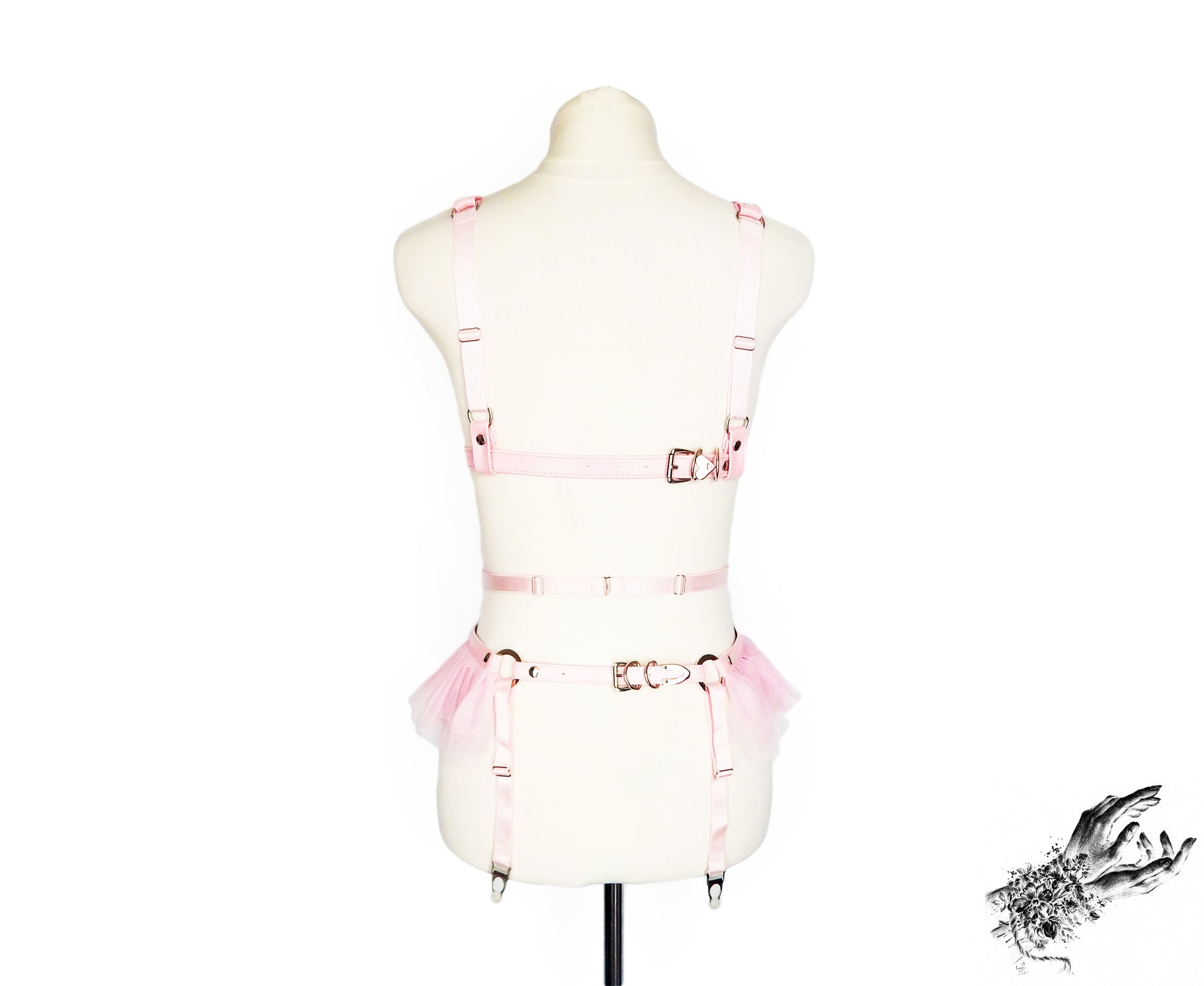 Rear view of a pink faux leather harness set featuring a separate harness bra and garter belt with adjustable elastic and buckled faux leather straps, displayed on a mannequin against a white background.