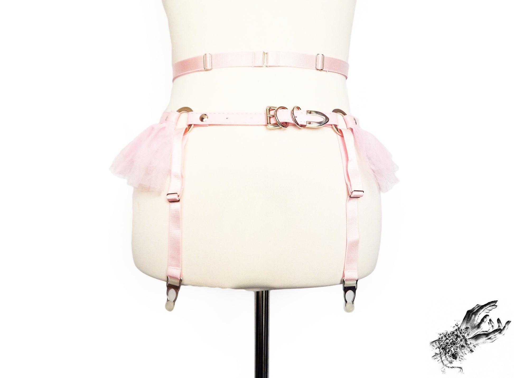 Rear view of a pink faux leather garter belt featuring showing the adjustable elastic and vegan leather waist and hip straps as well as adjustable elastic suspender straps, displayed on a mannequin against a white background.