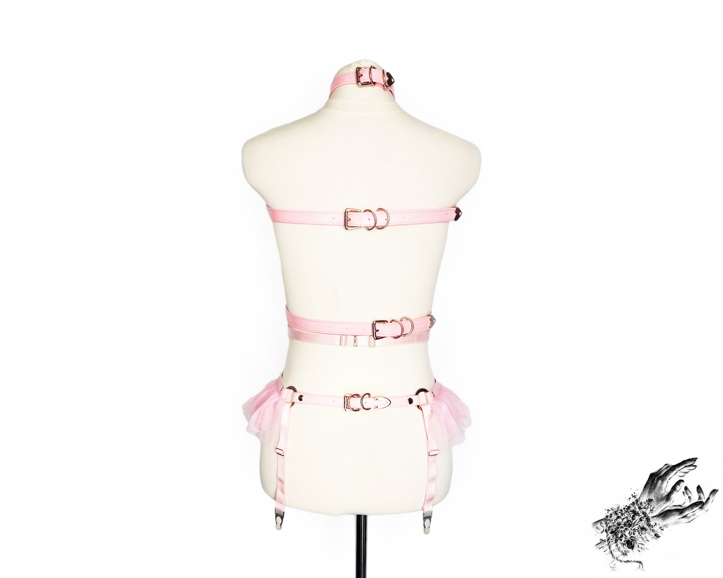 Rear view of a pink vegan leather harness set featuring a separate top harness and garter belt with adjustable elastic and faux leather buckled straps, displayed on a mannequin against a white background.