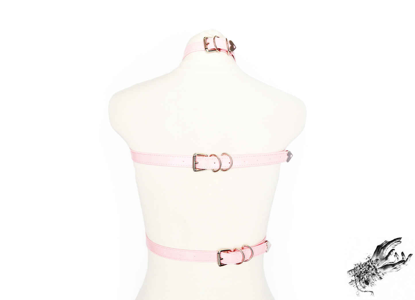 Rear view of a pink vegan leather top harness featuring silver O ring hardware and adjustable neck, chest and waist straps, displayed on a mannequin against a white background.