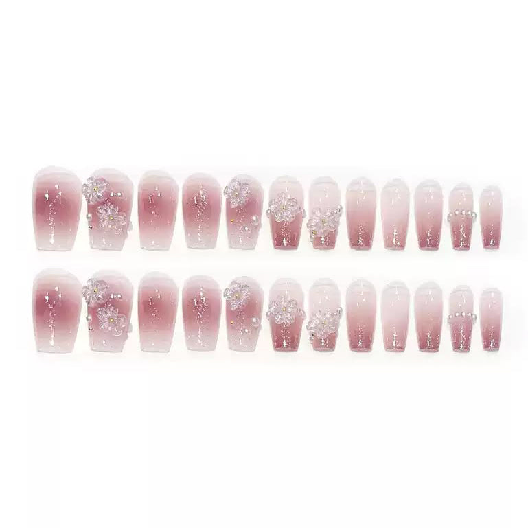 medium length ballerina tip nude and pink glitter false nails featuring 3D sculpted flowers and white pearl beads, displayed on a white background.