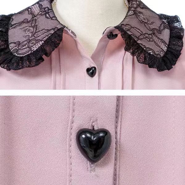 Close-up of a pink and black long sleeved blouse, showing the black lace trimmed Peter Pan collar and heart shaped buttons. Displayed on a mannequin against a white background.